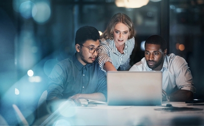 Three young coworkers working around laptop